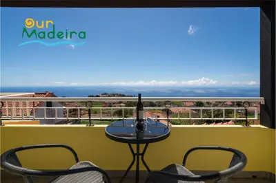 a table on a balcony with a view of the ocean at OurMadeira - Yellow House in Raposeira do Logarinho