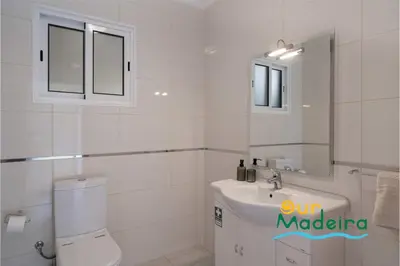 a white bathroom with a toilet and a sink at OurMadeira - Yellow House in Raposeira do Logarinho