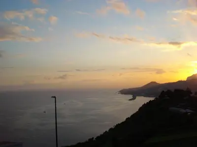 a sunset over a body of water with a street light at Villa São Paulo in Funchal