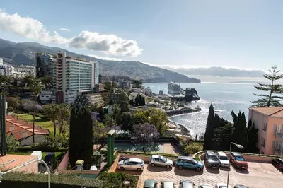 a city with cars parked in a parking lot next to the water at Monumental Miramar Apartment by Rent-a-key in Funchal