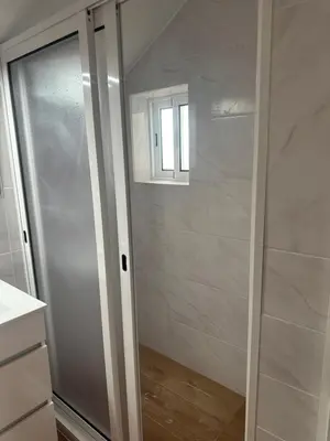 a glass shower door in a bathroom with a window at Gori House in Madalena do Mar