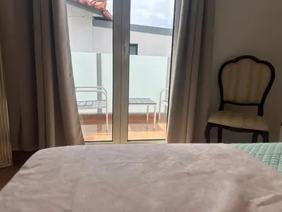 a bedroom with a bed and a chair and a window at Gori House in Madalena do Mar