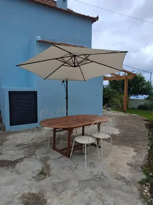 a wooden table and chairs with a large umbrella at The Blue Cottage in Gaula