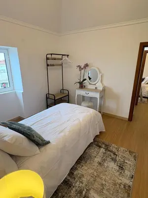 a bedroom with a bed with a yellow chair and a mirror at The Blue Cottage in Gaula