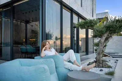 a woman sitting on a couch talking on a cell phone at Saudade Residence - Ultra Luxury Futuristic Ocean Zen Retreat in Ribeira Brava