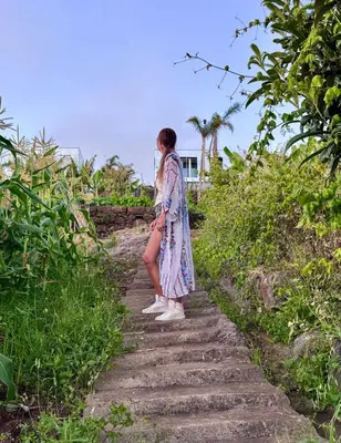 a woman is standing on a stone path near the ocean at Saudade Residence - Ultra Luxury Futuristic Ocean Zen Retreat in Ribeira Brava
