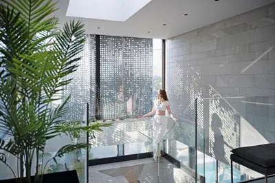 a woman standing on a glass balcony looking out at the city at Saudade Residence - Ultra Luxury Futuristic Ocean Zen Retreat in Ribeira Brava