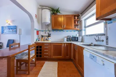 a kitchen with wooden cabinets and a table and a refrigerator at incredible view- T1 Salema in Salema