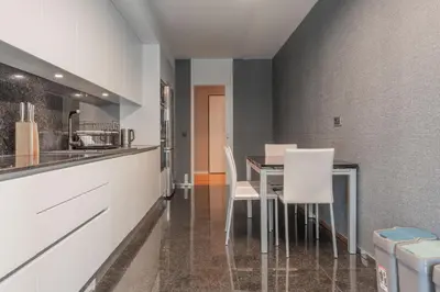 a kitchen with white cabinets and a table and chairs at FLH Funchal Elegant Apartment with Pool & Balcony in Funchal