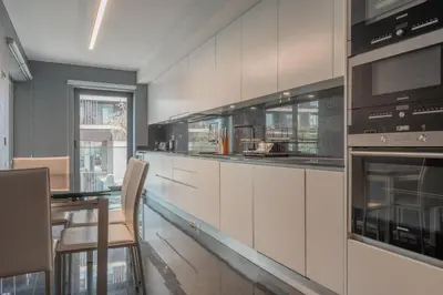 a kitchen with white cabinets and a table with chairs at FLH Funchal Elegant Apartment with Pool & Balcony in Funchal