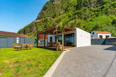 a house with a mountain in the background at Fajã Lodges - House Ash in São Vicente
