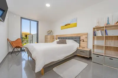 a bedroom with a large bed and a chair at Fajã Lodges - House Ash in São Vicente