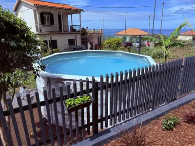 a fence with a pool in front of a house at Fajã Lodges - House Ash in São Vicente