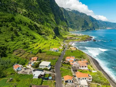 a village on a hill next to the ocean at Fajã Lodges - House Ash in São Vicente