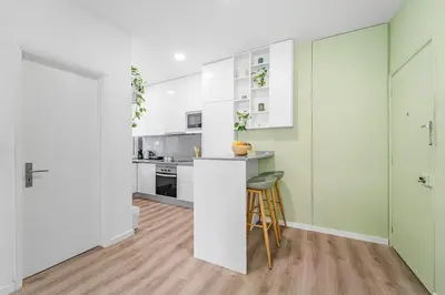 a kitchen with white cabinets and a bar with a stool at Green Living-Funchal in Funchal