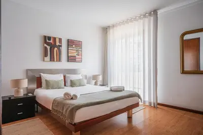 a bedroom with a large white bed with two lamps at Portola Penthouse by YMR in Funchal