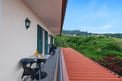 a balcony of a house with a table and chairs at Miradouro House By Sam Houses in Ponta do Sol