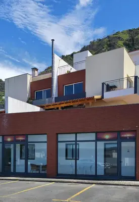 a red brick building with a balcony at Pôr do Sol II in Porto Moniz