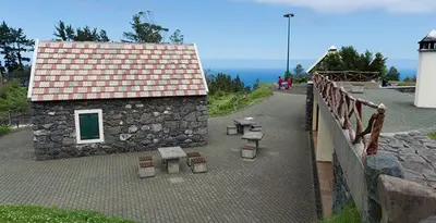 a stone building with benches next to a bridge at Pôr do Sol II in Porto Moniz
