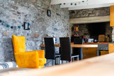 a bar with yellow chairs and a stone wall at GuestReady – Rustic Charm in Peaceful Madeira in Porto da Cruz