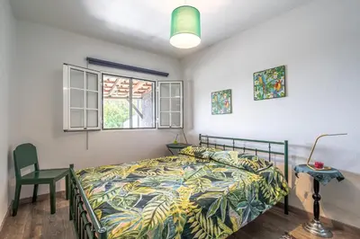 a bedroom with a bed and a chair and a window at Casa de Campo Serrão in Calheta