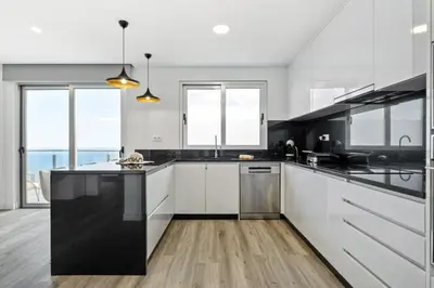 a kitchen with white cabinets and a black counter top at Villa Vellure by Homie in Funchal