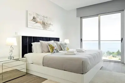 a white bedroom with a large bed and a large window at Villa Vellure by Homie in Funchal