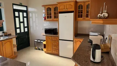 a kitchen with a white refrigerator and wooden cabinets at Villa Serenity in Porto Moniz