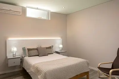 a bedroom with a bed and two chairs and a window at Casa da Relva com Piscina Aquecida Interna in Arco da Calheta