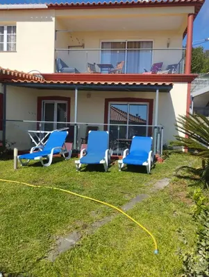 a house with two blue chairs and a hose at Casa da Relva com Piscina Aquecida Interna in Arco da Calheta