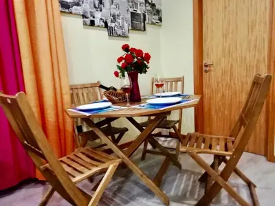 a table with two chairs and a vase with red flowers at Casa da Relva com Piscina Aquecida Interna in Arco da Calheta