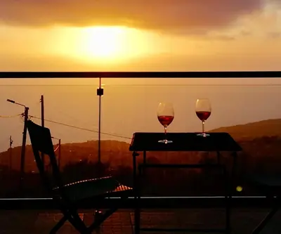 two glasses of wine sitting on a table in front of the sunset at Casa da Relva com Piscina Aquecida Interna in Arco da Calheta