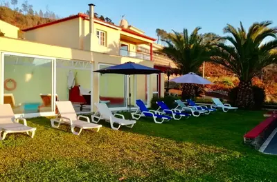 a group of chairs and umbrellas on a yard at Casa da Relva com Piscina Aquecida Interna in Arco da Calheta