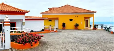 a yellow house with flowers in front of it at Apartamento Villa 4 in Ponta do Sol