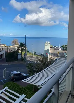 a balcony with a view of a parking lot and the ocean at Modern Urban Apartment in Funchal