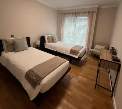 a bedroom with two beds and a chair and a window at Modern Urban Apartment in Funchal