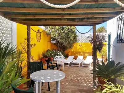 a patio with white tables and chairs and a yellow wall at Villa Sorriso in Luz