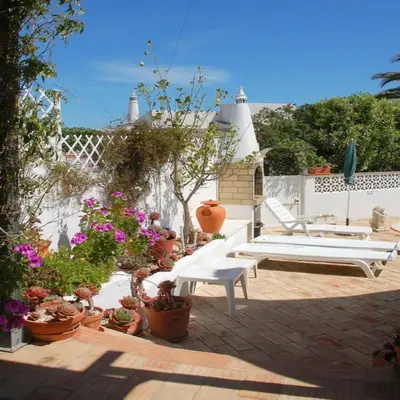 a patio with a white bench and potted plants at Villa Sorriso in Luz
