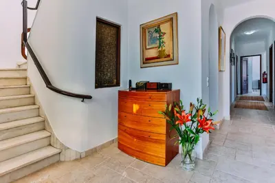 a hallway with stairs and a dresser with a vase of flowers at Fawlty Towers in Luz