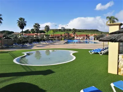 a pool at a resort with chairs and a lawn at Boavista 59A in Lagos