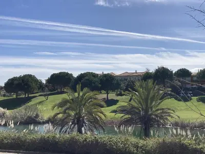 a golf course with palm trees and a pond at Boavista 59A in Lagos