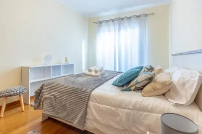 a bedroom with a bed with pillows and a window at Cantinho da Ribeira in Machico