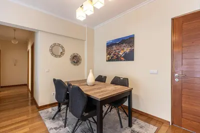 a dining room with a wooden table and chairs at Cantinho da Ribeira in Machico