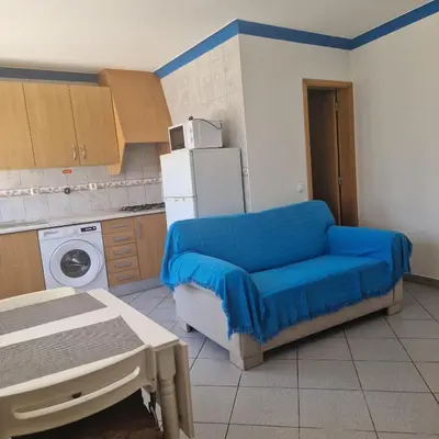 a kitchen with a blue couch and a refrigerator at Apartamento T1 -Sagres in Sagres