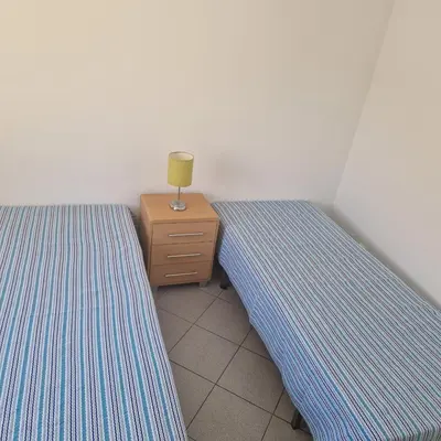 a bedroom with two beds and a lamp on a dresser at Apartamento T1 -Sagres in Sagres