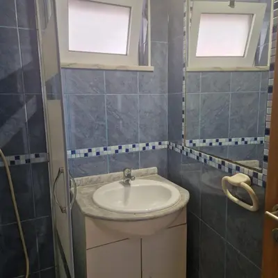 a bathroom with a sink and two windows at Apartamento T1 -Sagres in Sagres
