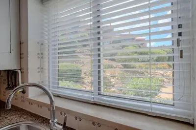 a kitchen window with blinds over a kitchen sink at Ocean View with Private Terrace in Luz