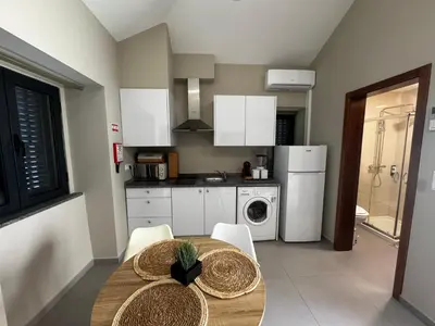 a kitchen with a table and chairs and a kitchen with white appliances at São Pedro Paradise A UP in Funchal