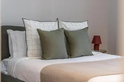 a bed with white pillows and a white wall at Quintinha Estrelícia - Pool and Garden in Funchal