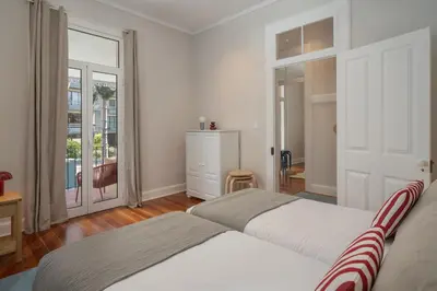 a bedroom with two beds and a sliding glass door at Quintinha Estrelícia - Pool and Garden in Funchal